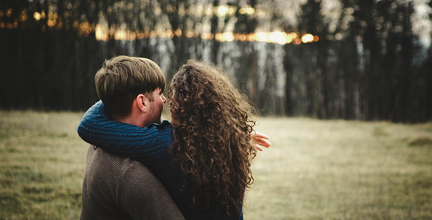 Romantic couple hugging outdoors in a natural landscape at sunset