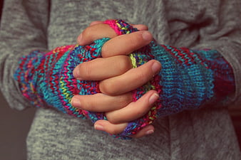 Close-up of hands wearing colorful knitted fingerless gloves