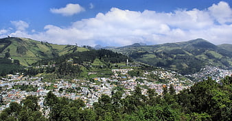 Panoramic View of Town Nestled in Green Hills Under Blue Sky