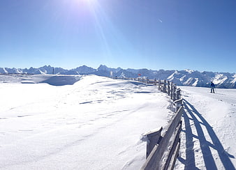 Sunny Winter Mountain Ski Slope with Wooden Fence