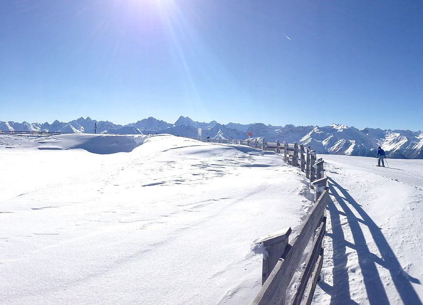 Sunny Winter Mountain Ski Slope with Wooden Fence