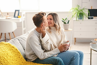 Happy couple kissing on sofa in bright living room