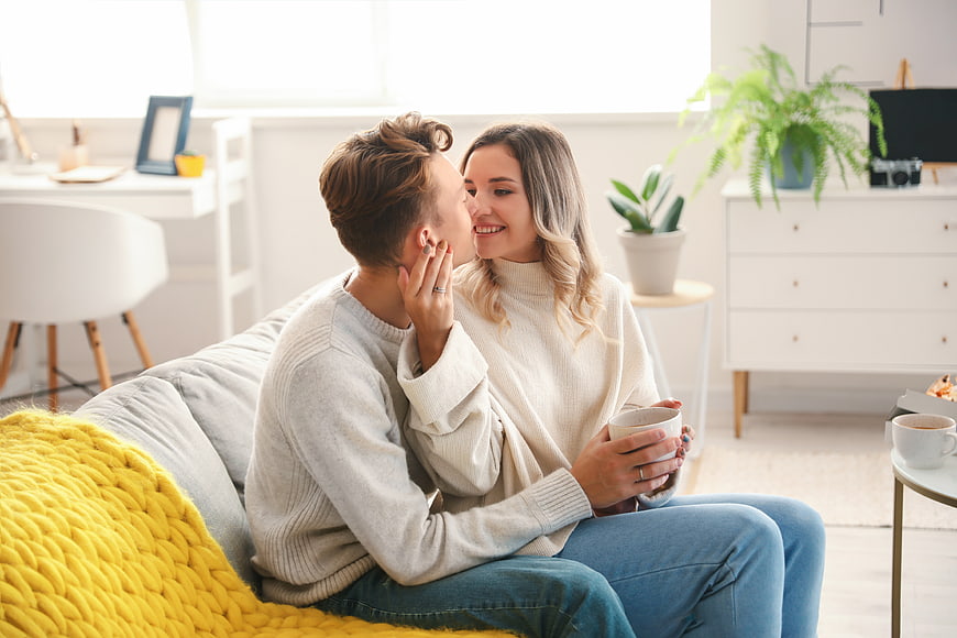 Happy couple kissing on sofa in bright living room