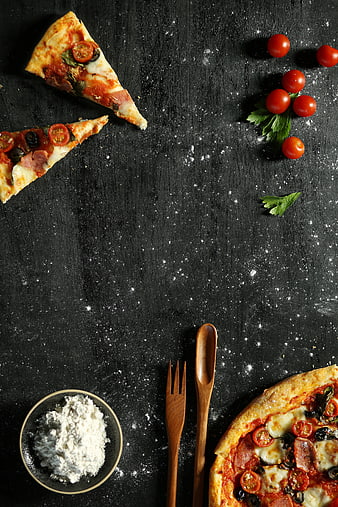 Flat lay of pizza slices and ingredients on dark background