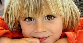 Close-up portrait of a smiling young child with blonde hair