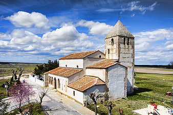 Historic stone church with bell tower in rural landscape
