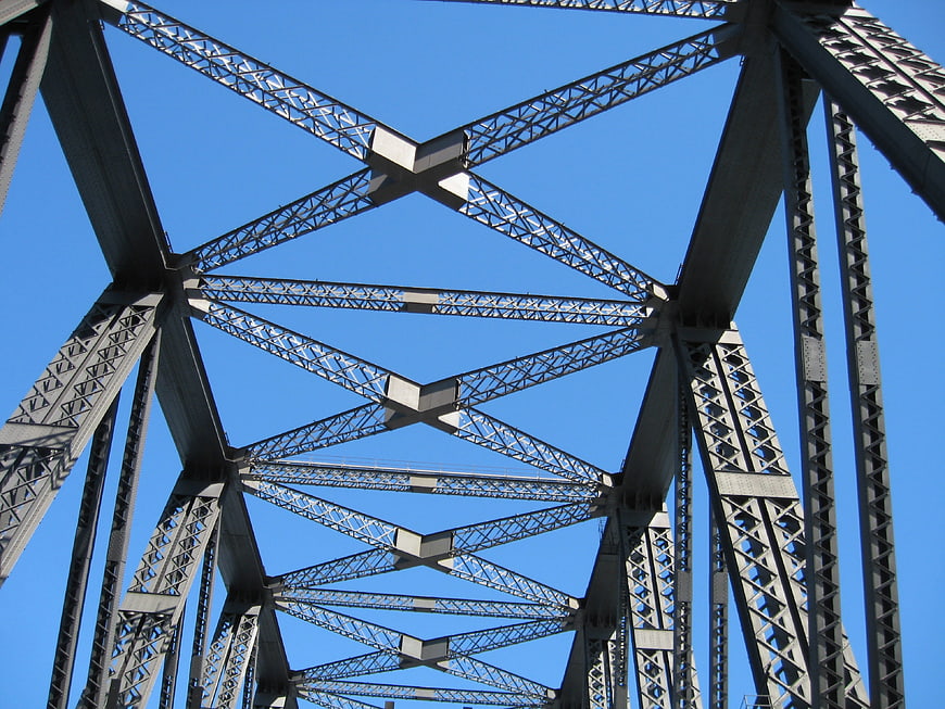 Low angle view of steel bridge truss against blue sky