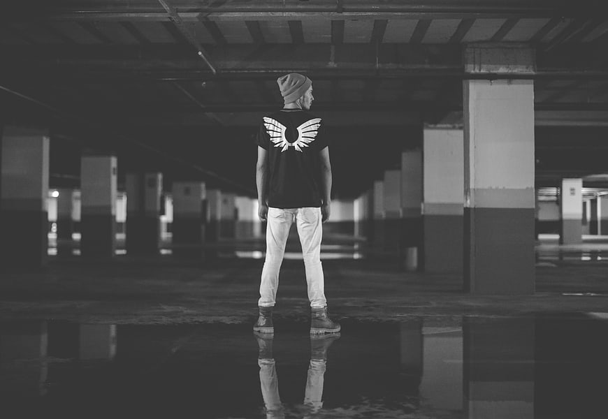 Man standing alone in dark parking garage with reflection