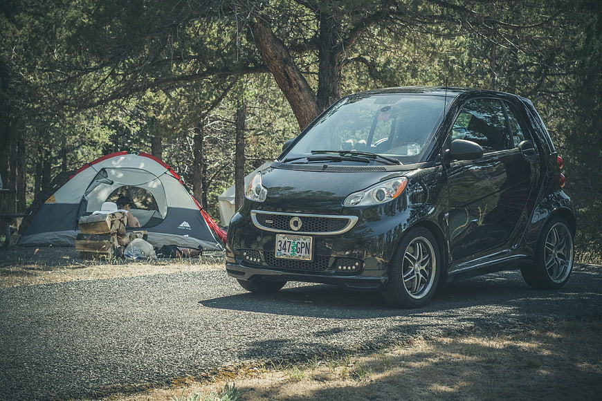 Black Smart Car Parked at Forest Campsite