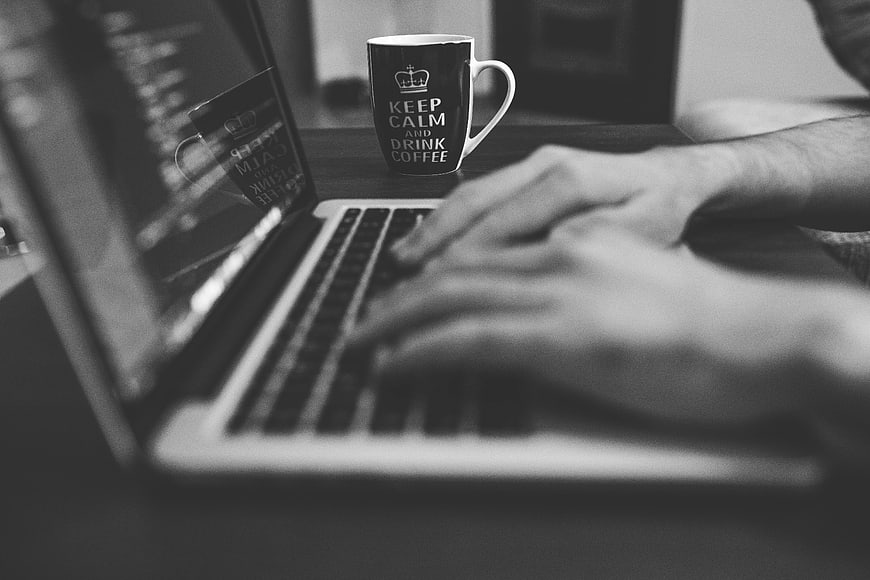 Person Typing on Laptop with Coffee Mug