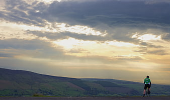 Cyclist on Road Overlooking Rolling Hills at Sunset