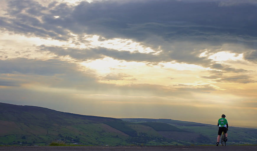 Cyclist on Road Overlooking Rolling Hills at Sunset