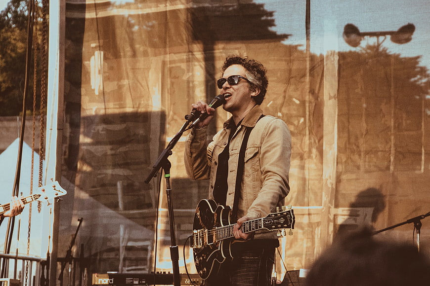Male musician singing and playing guitar on stage