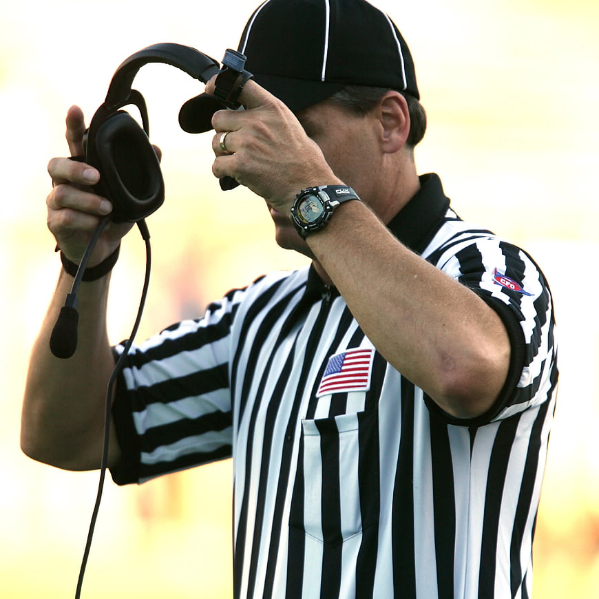 Football Referee Adjusting Headset on Field