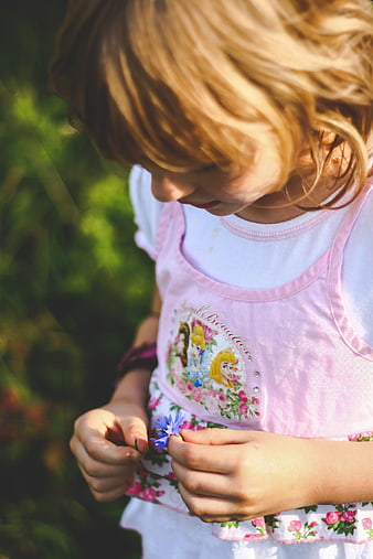Little girl holding blue flower in pink dress