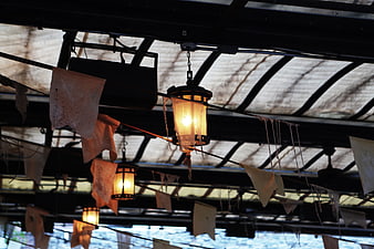 Rustic Hanging Lanterns and Tattered Banners Under Metal Roof
