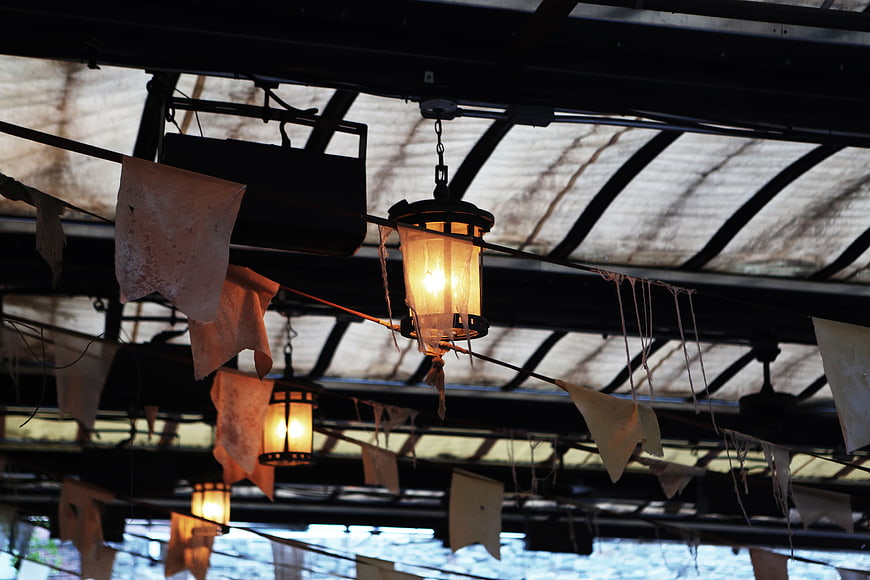 Rustic Hanging Lanterns and Tattered Banners Under Metal Roof