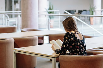 Woman reading book in modern library study space