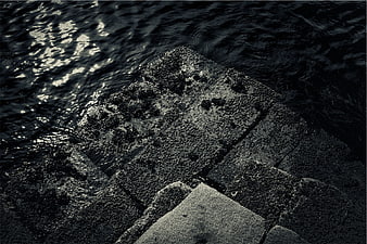 Dark textured concrete steps meeting rippling water at night