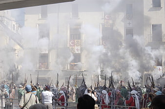 Historical reenactment with muskets and smoke in a town square