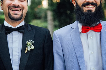 Two smiling groomsmen in suits with bow ties
