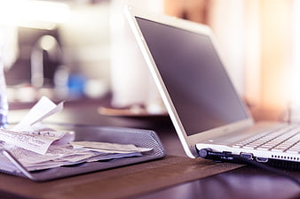 White laptop and receipts on wooden desk