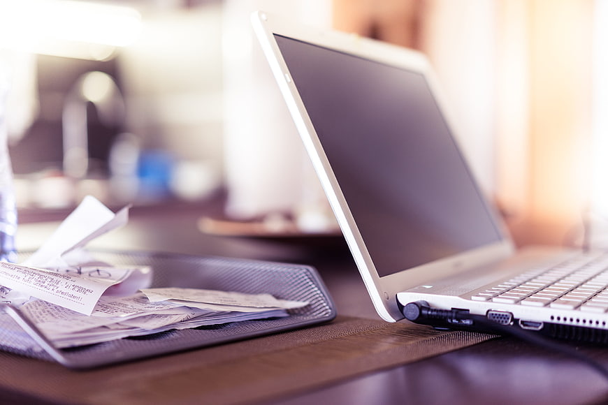 White laptop and receipts on wooden desk