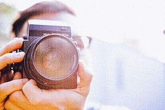 Close-up of hands holding vintage film camera lens