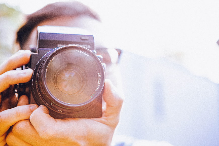 Close-up of hands holding vintage film camera lens