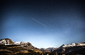 Starry Night Sky Over Snow-Capped Mountain Range