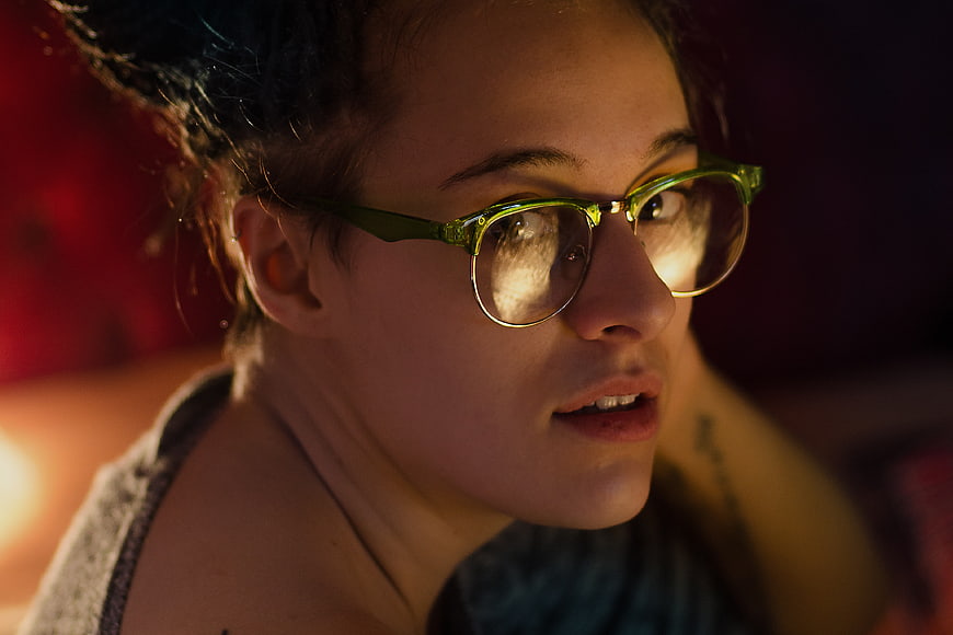 Woman with glasses looking at screen in dim light