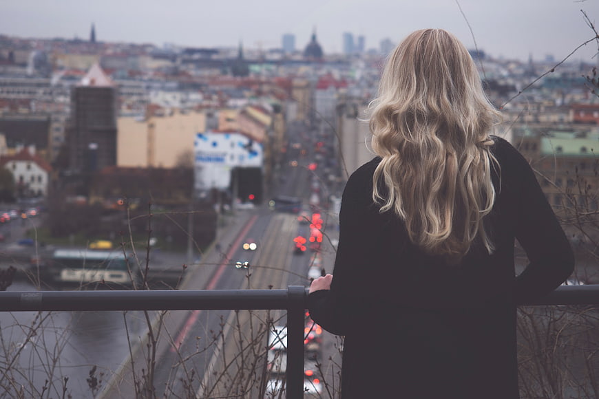 Woman with blonde hair looking at city skyline from bridge