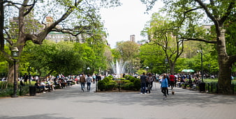 Crowded City Park Path with Fountain and Trees