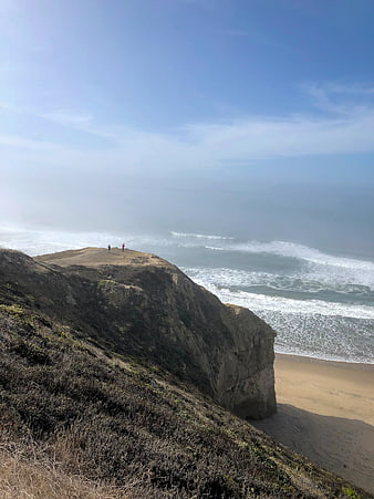 Scenic coastal cliff view with ocean waves and hikers