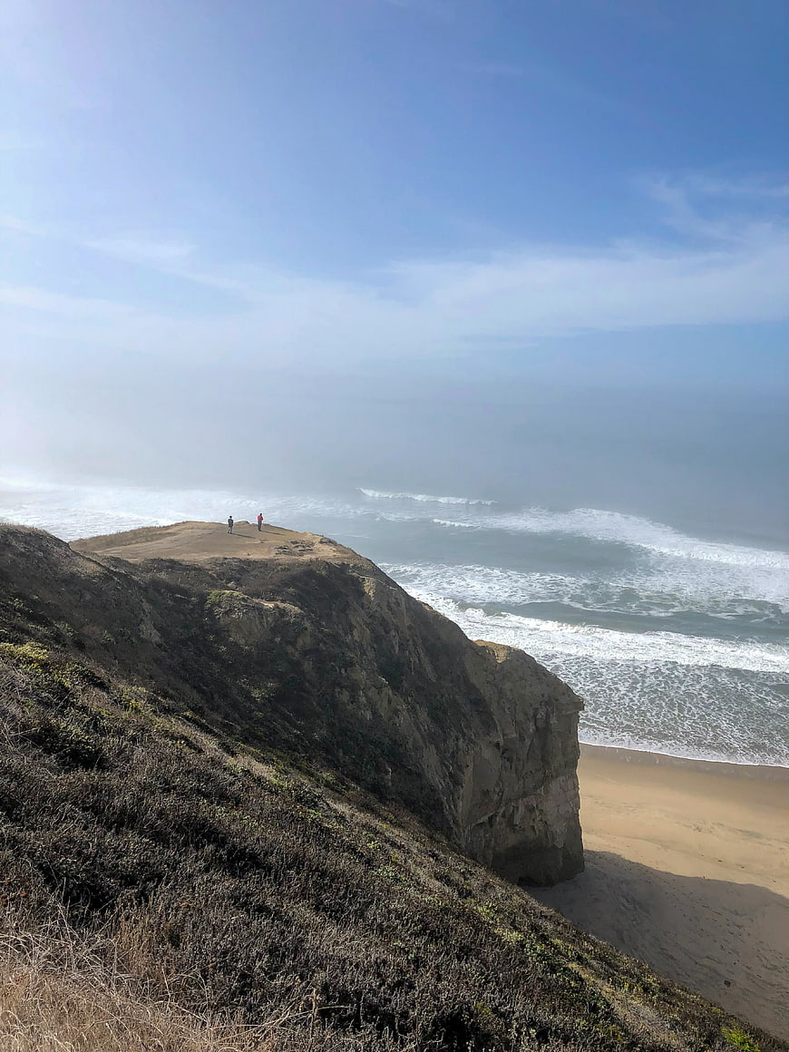 Scenic coastal cliff view with ocean waves and hikers