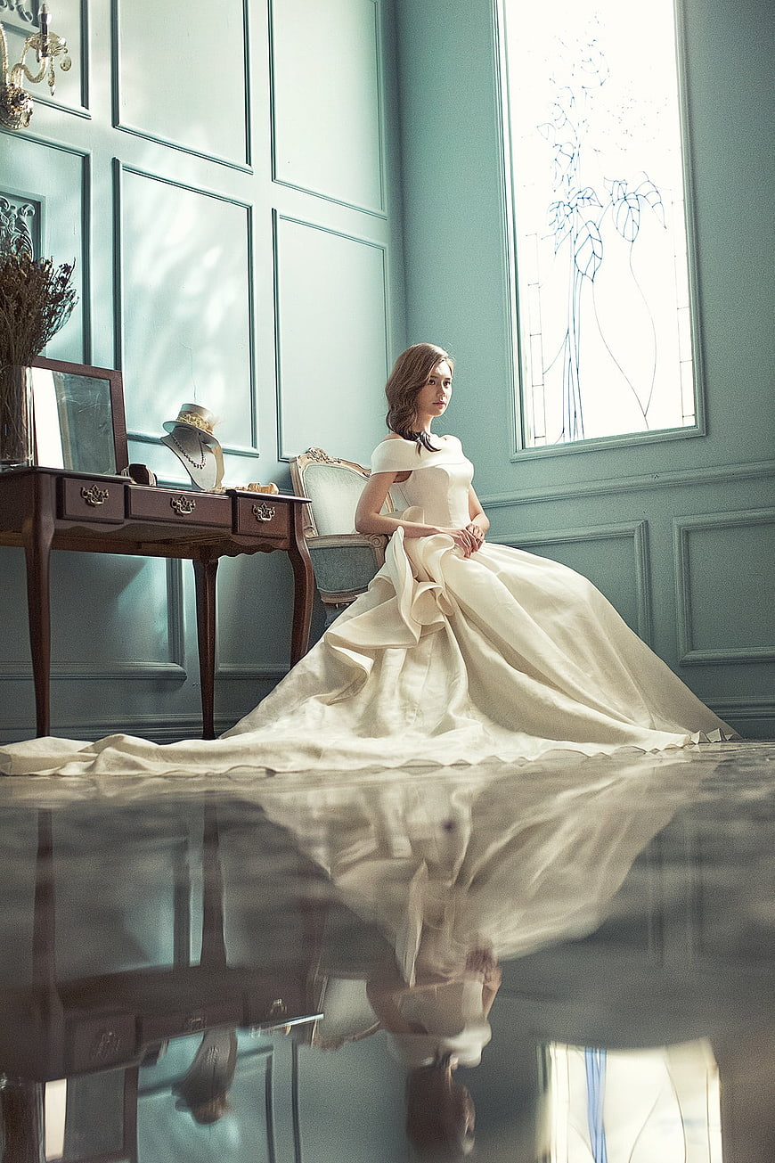 Elegant Bride in White Gown Sitting in Blue Room