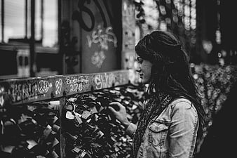 Woman touching love locks on bridge railing in black and white