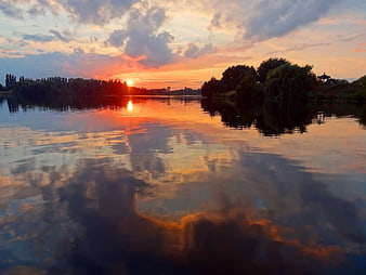 Serene Sunset Reflection on Calm River with Silhouetted Trees
