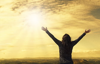 Woman with arms raised to the sun in a golden landscape