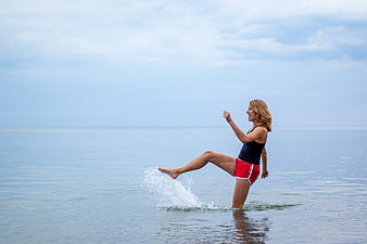 Happy woman kicking water splash on calm beach
