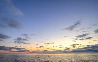 Serene sunset over calm ocean with scattered clouds
