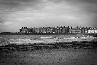 Black and white coastal town with row houses and rough sea