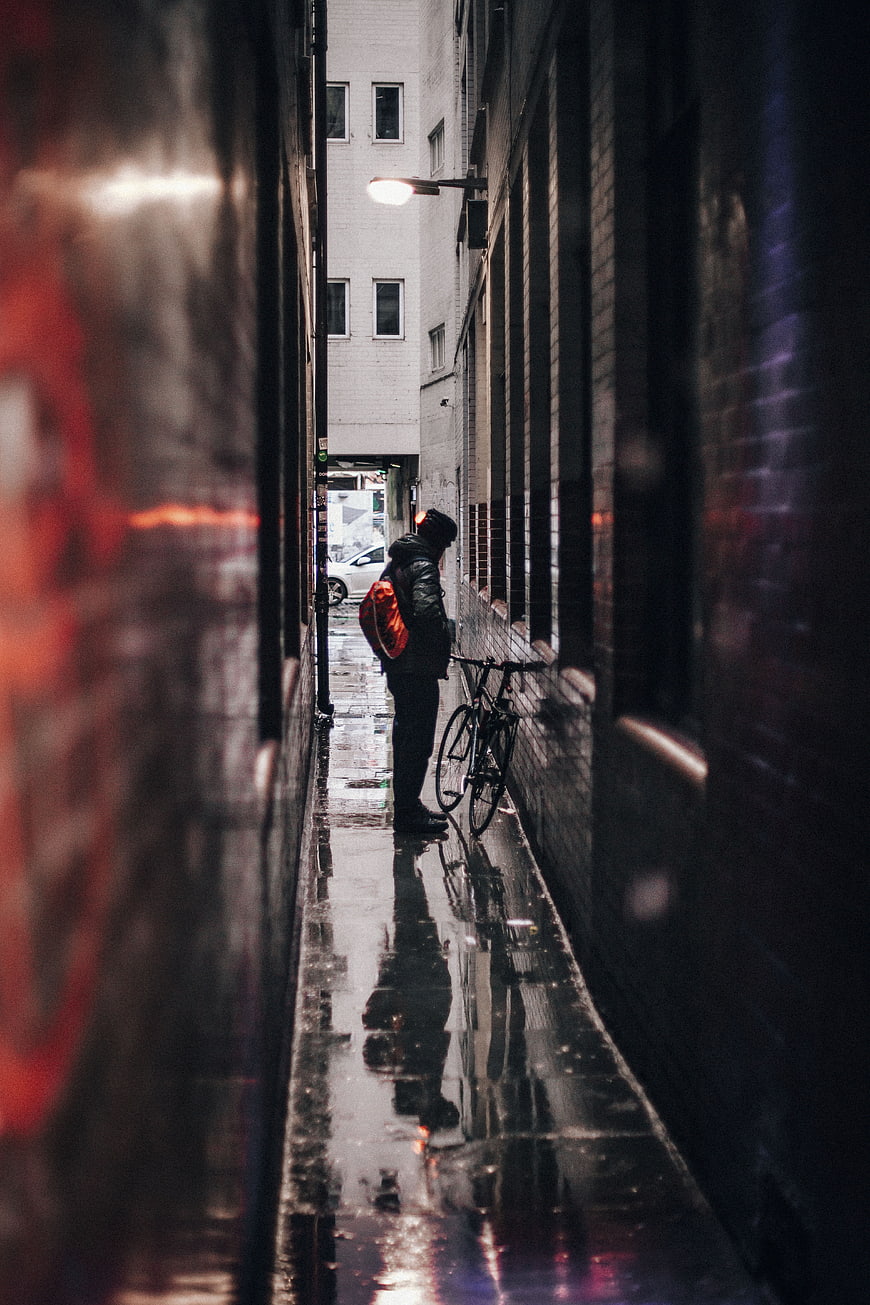 Lone Cyclist in Rainy Urban Alley at Night