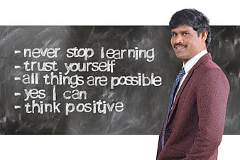 Smiling businessman standing next to motivational chalkboard quotes