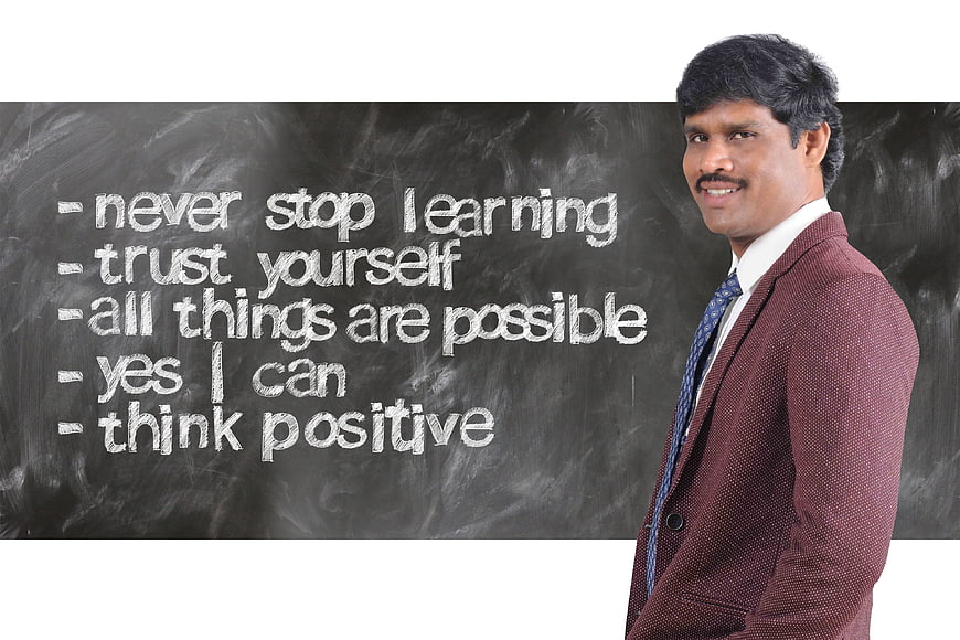 Smiling businessman standing next to motivational chalkboard quotes