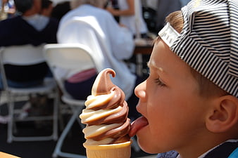 Boy licking chocolate and vanilla soft serve ice cream cone