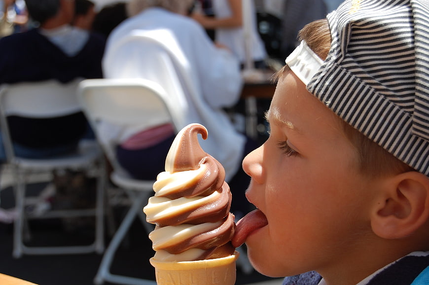 Boy licking chocolate and vanilla soft serve ice cream cone