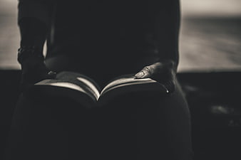 Close-up of hands holding an open book in moody lighting