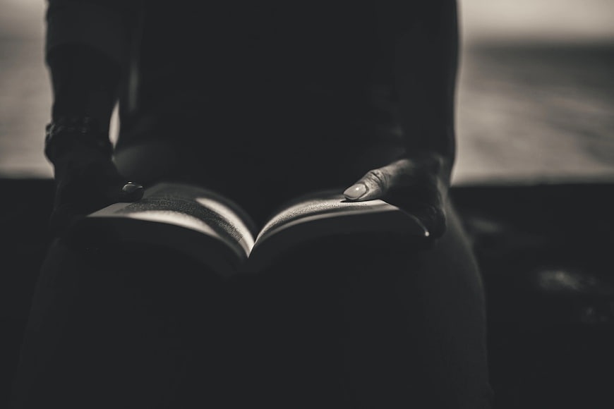 Close-up of hands holding an open book in moody lighting