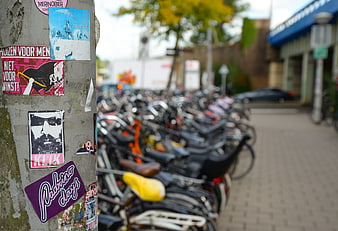Street pole with stickers and blurred row of parked bicycles